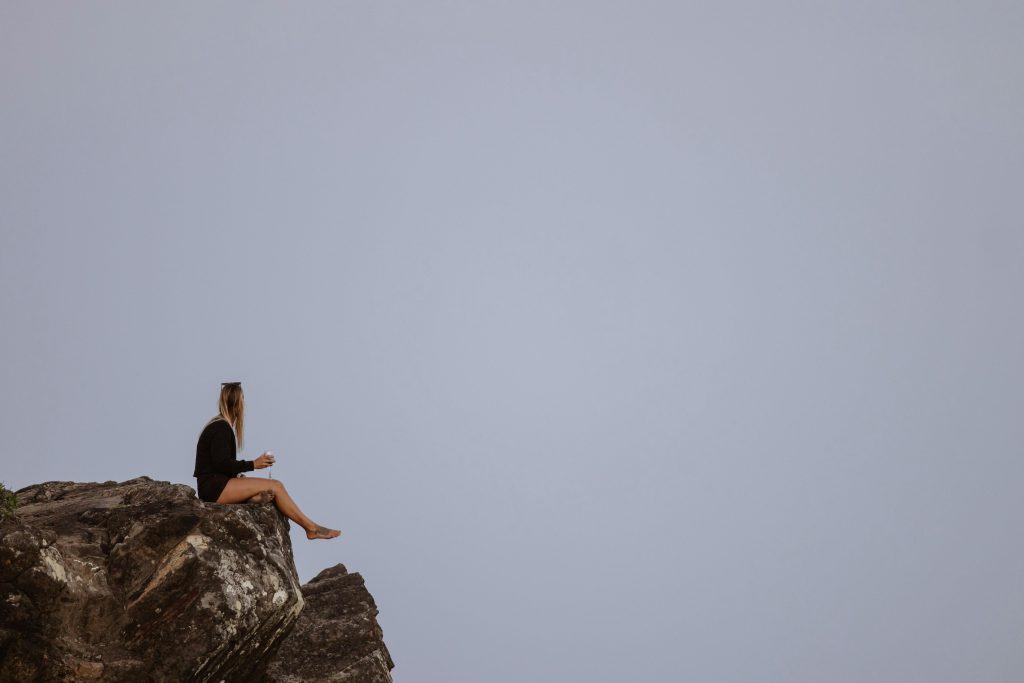 A woman sitting on a cliff edge, enjoying the coastal view at Cabarita Beach, Australia.